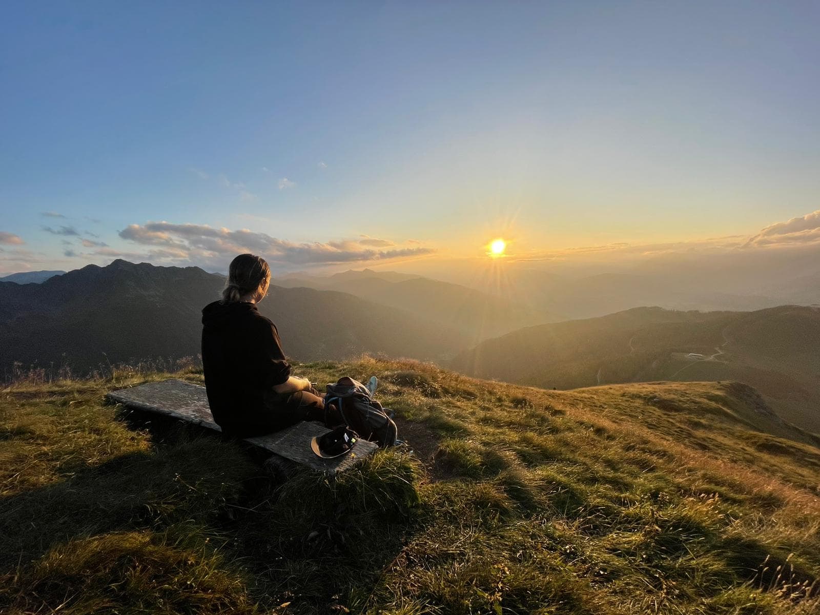 Person sitzt bei Sonnenuntergang