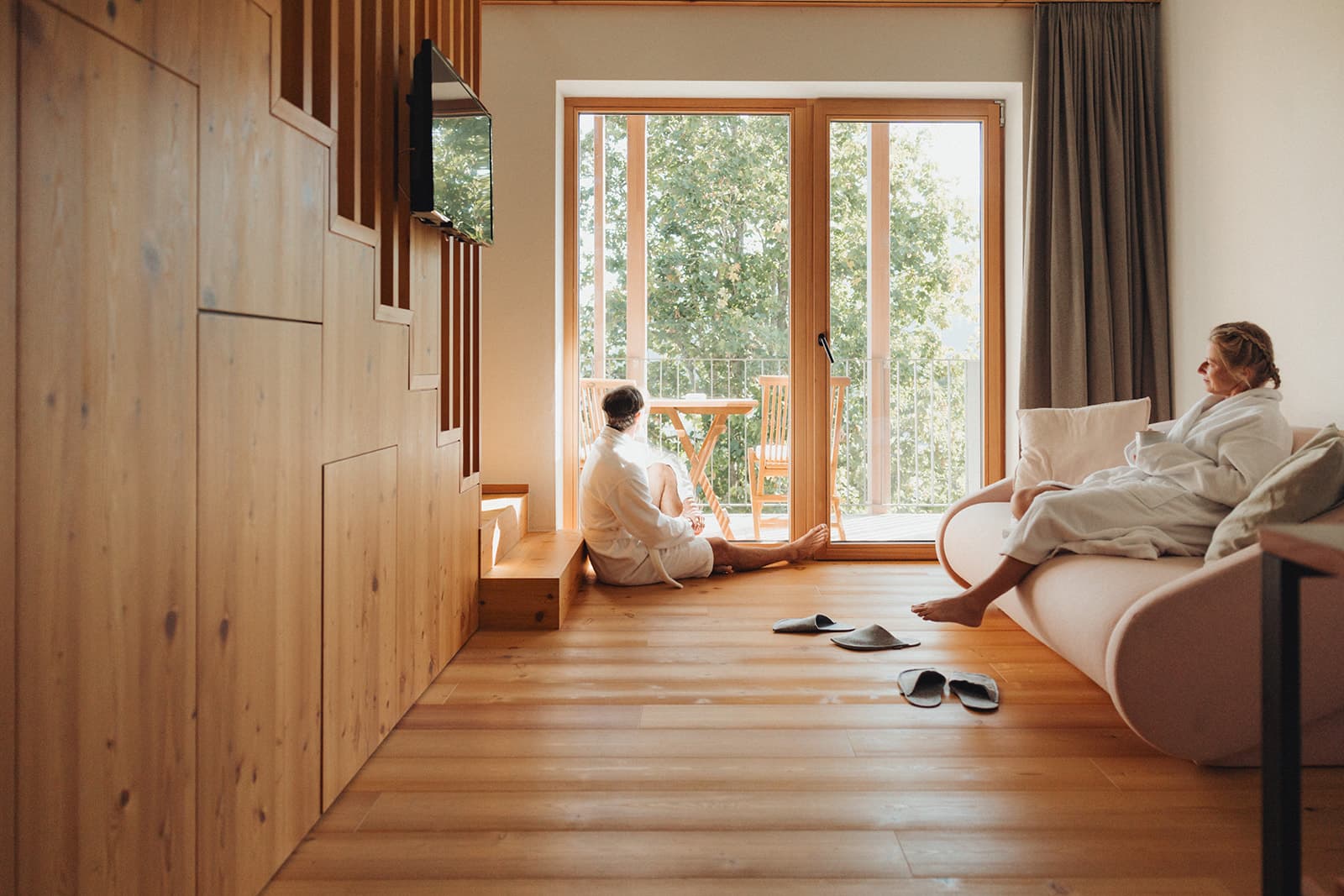 Flur mit Holz und Fenster und Personen sitzen am Boden und im Bett