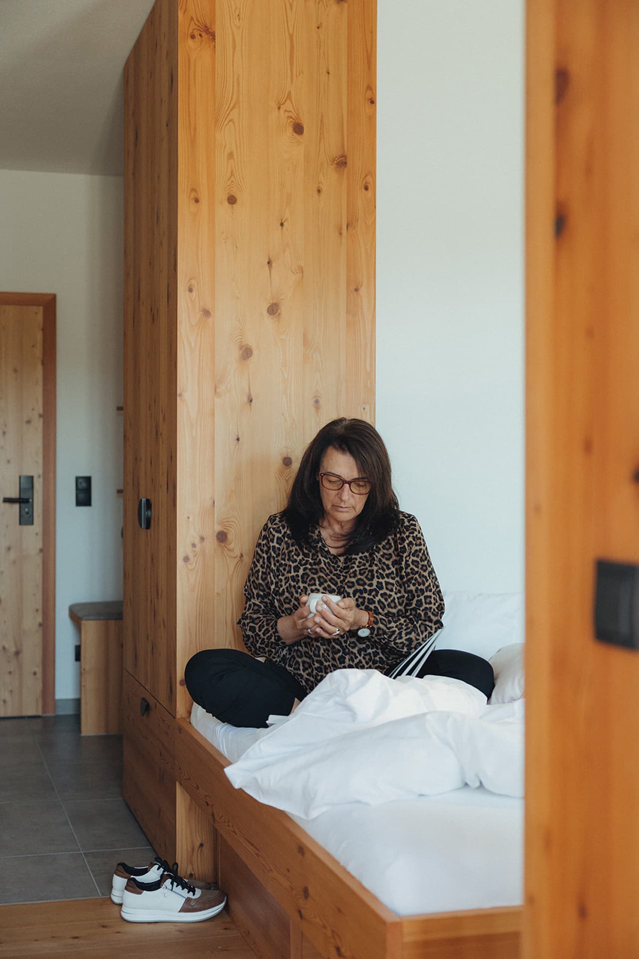 Frau sitzt am Bett mit Handy