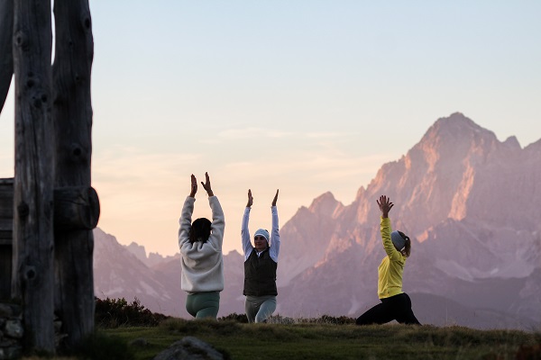 3 Frauen machen vor Bergkulisse Yoga