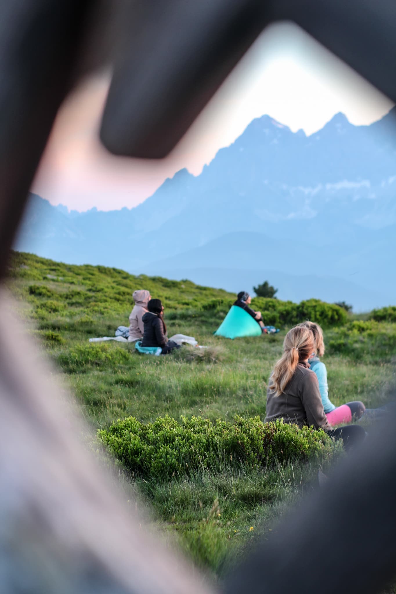 Person sitzt auf Wiese mit Bergblick
