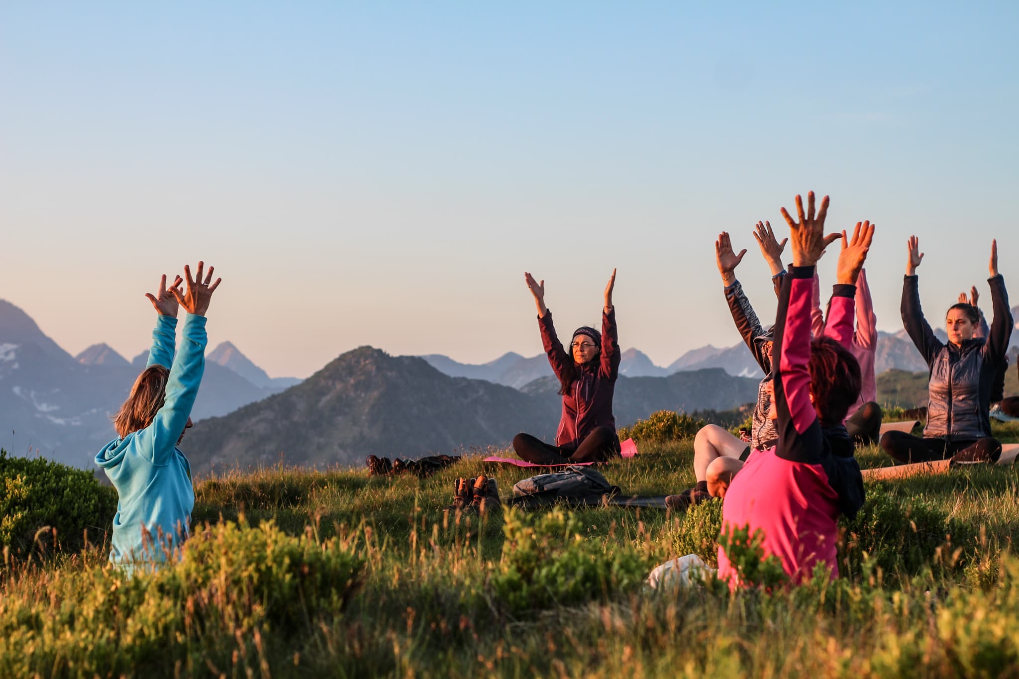 Gruppe hebt Hände in den Bergen beim yoga