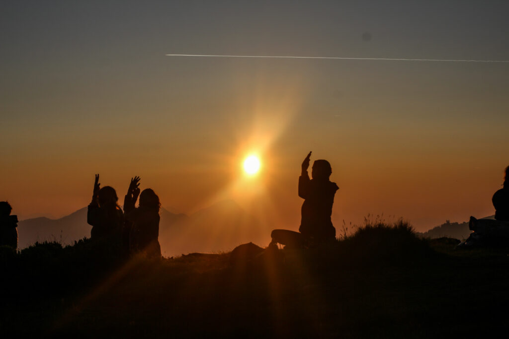 Menschen die Yoga machen vor Bergkulisse bei Sonnenaufgang