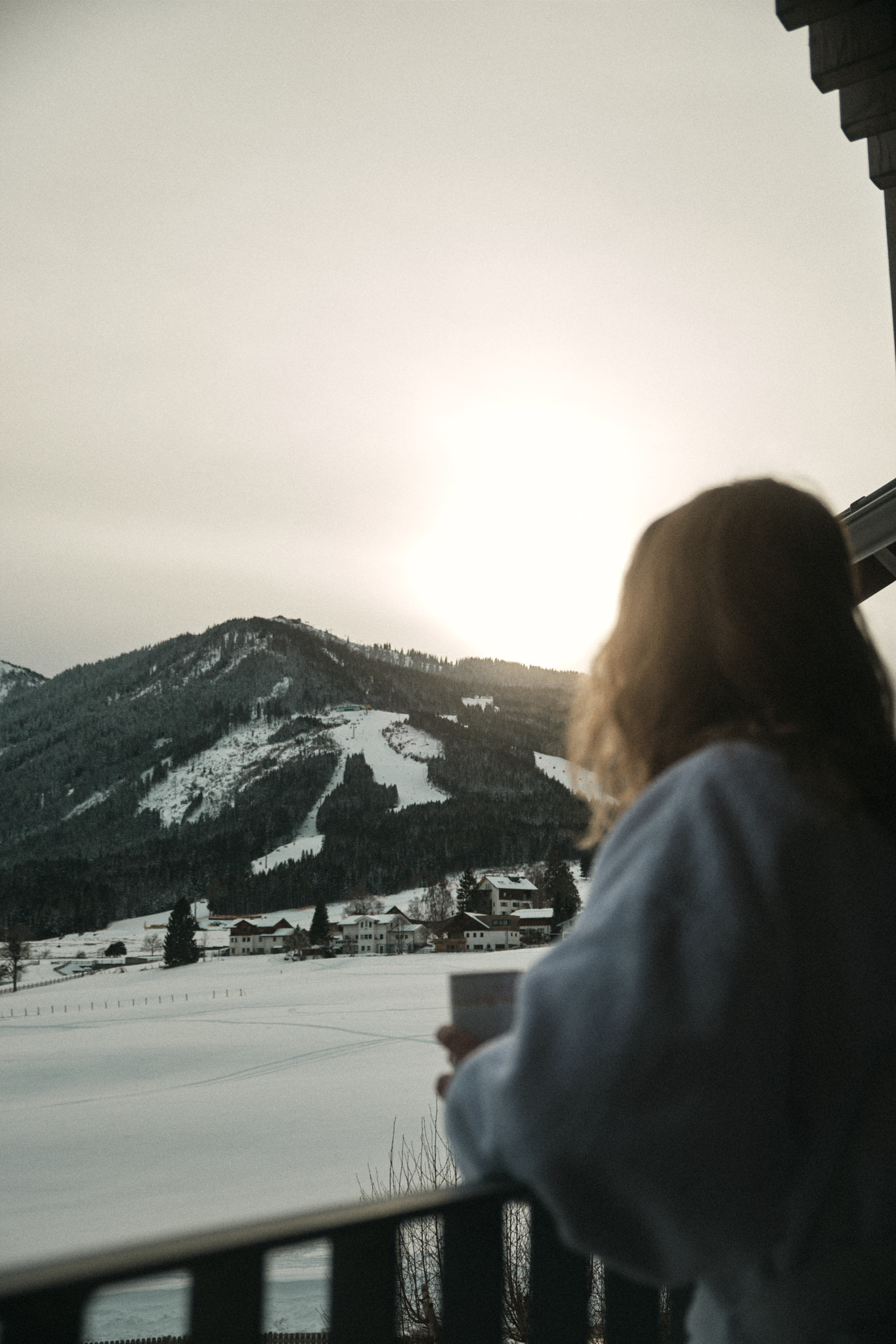 Frau blickt auf Berge vom Balkon
