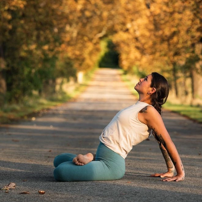 Frau sitz auf Straße und macht Yoga im Herbst