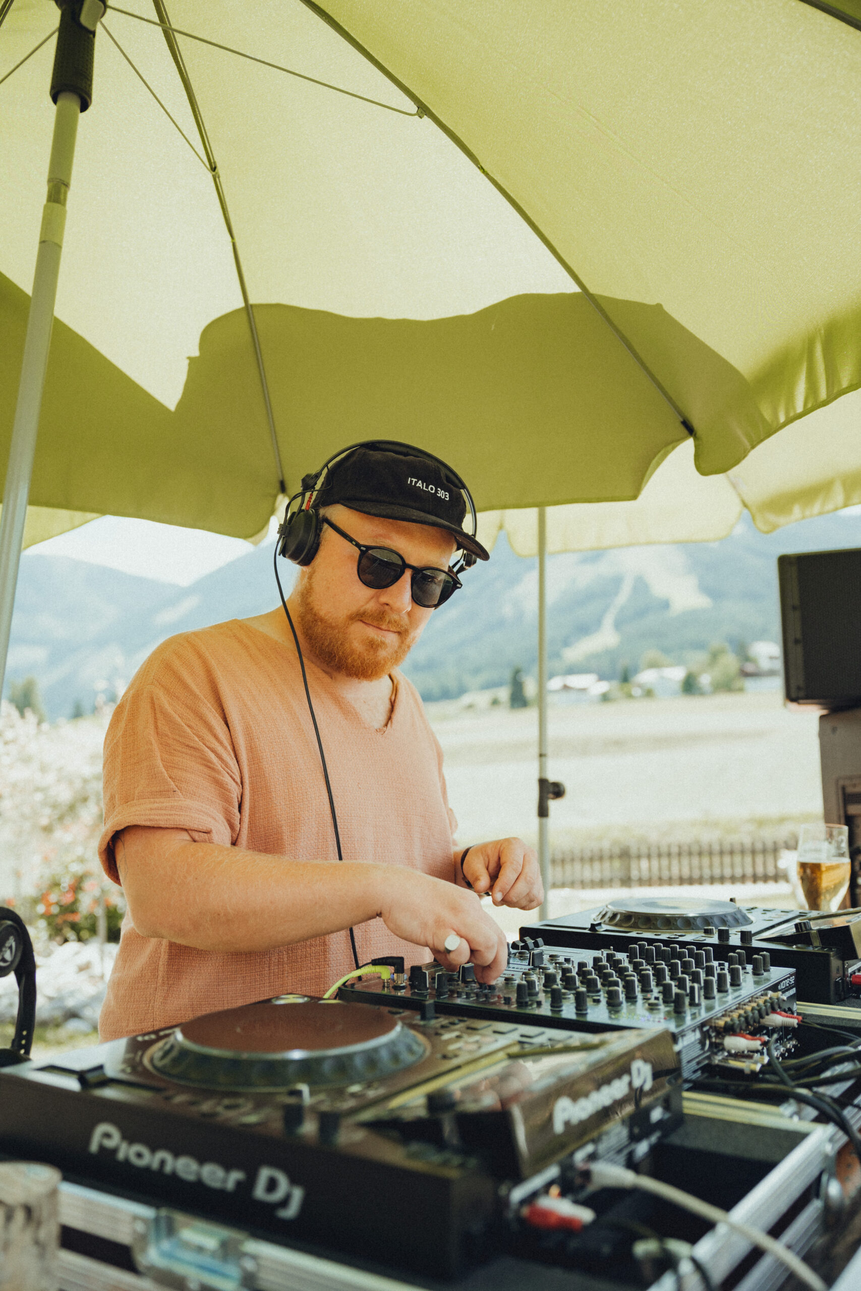 DJ mit Sonnebrille unter einem Sonnenschirm der gerade auflegt